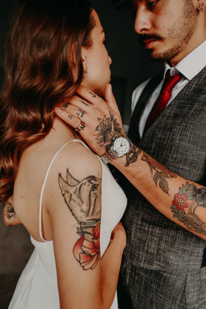 Tattooed couple in formal attire sharing an intimate moment, showcasing tattoos and elegance.