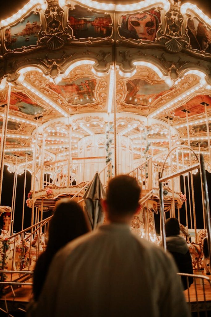 Couple enjoys a nighttime ride on an illuminated carousel.