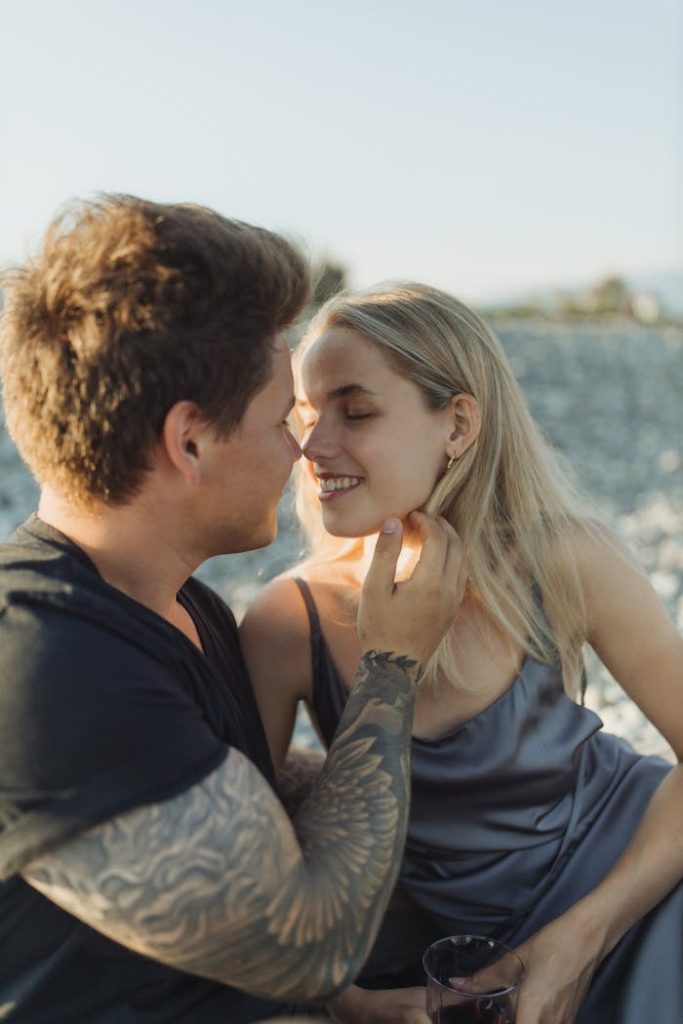 Romantic couple sharing a tender moment at a beach during sunset.