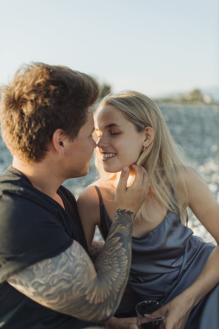 Romantic couple sharing a tender moment at a beach during sunset.